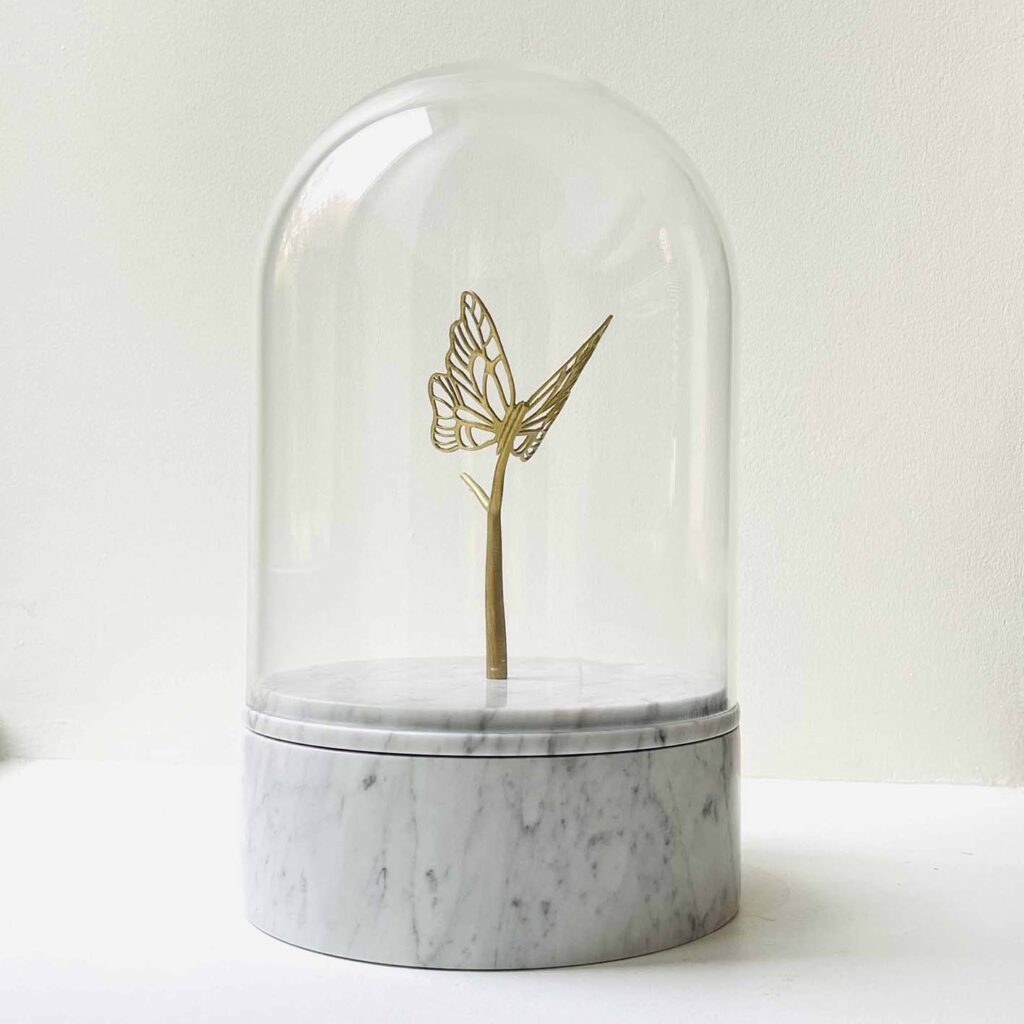 Marmeren urn met glazen stolp en gouden vlinder